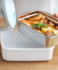 une personne qui met de l'eau dans la Boîte repas bento