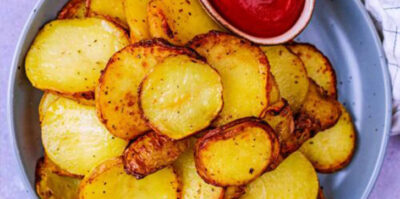 Une assiette de pommes de terre en tranches cuites avec un peu de ketchup.