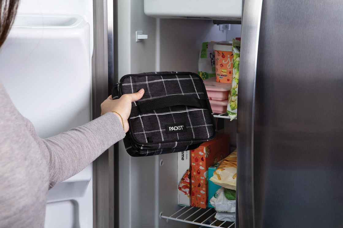 une femme plaçant un sac isotherme dans un réfrigérateur 